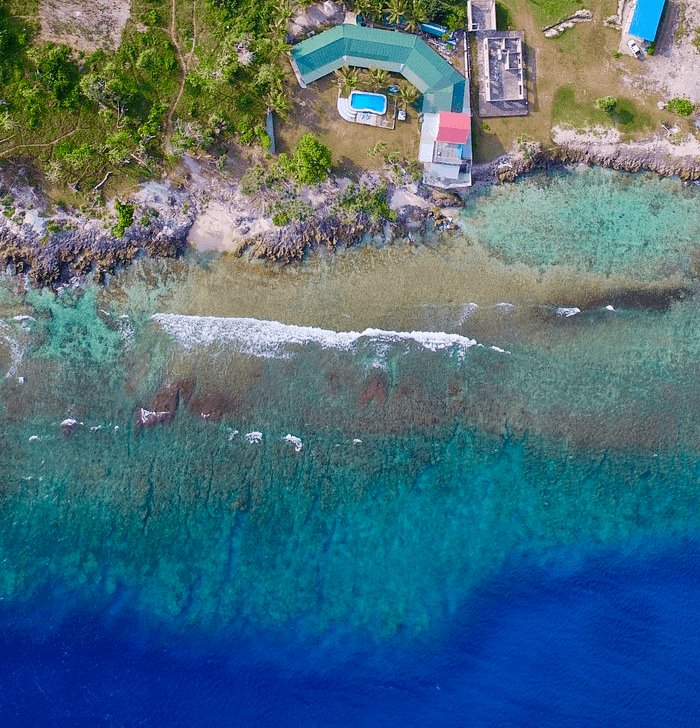 Close aerial view of Blue Pango Guesthouse directly above the reef at Pango Point, Vanuatu